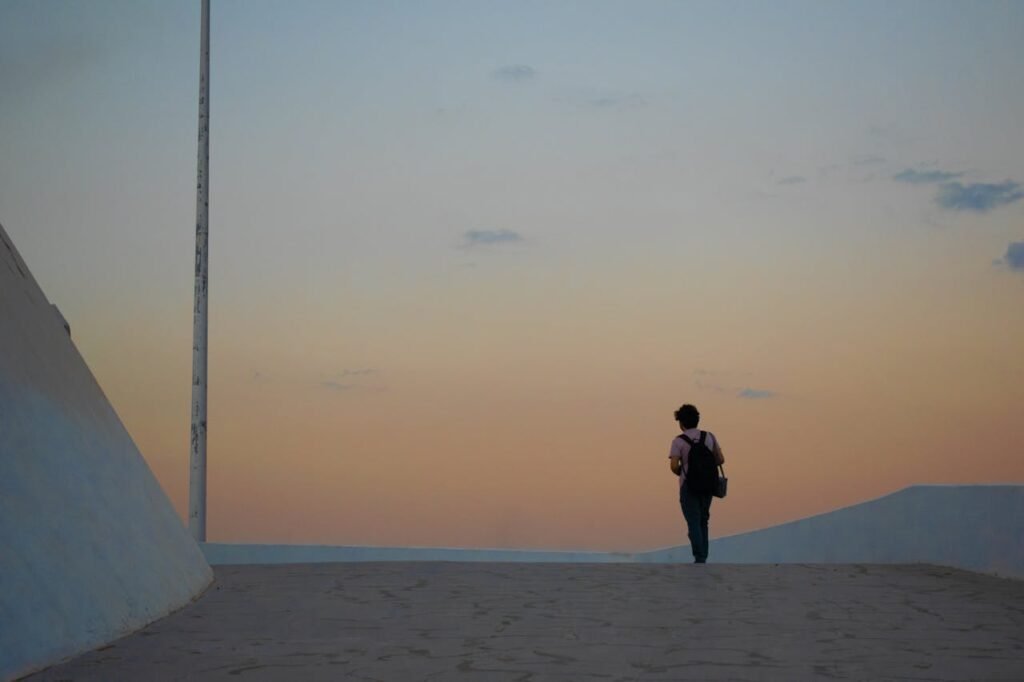 A person walking toward a sunrise