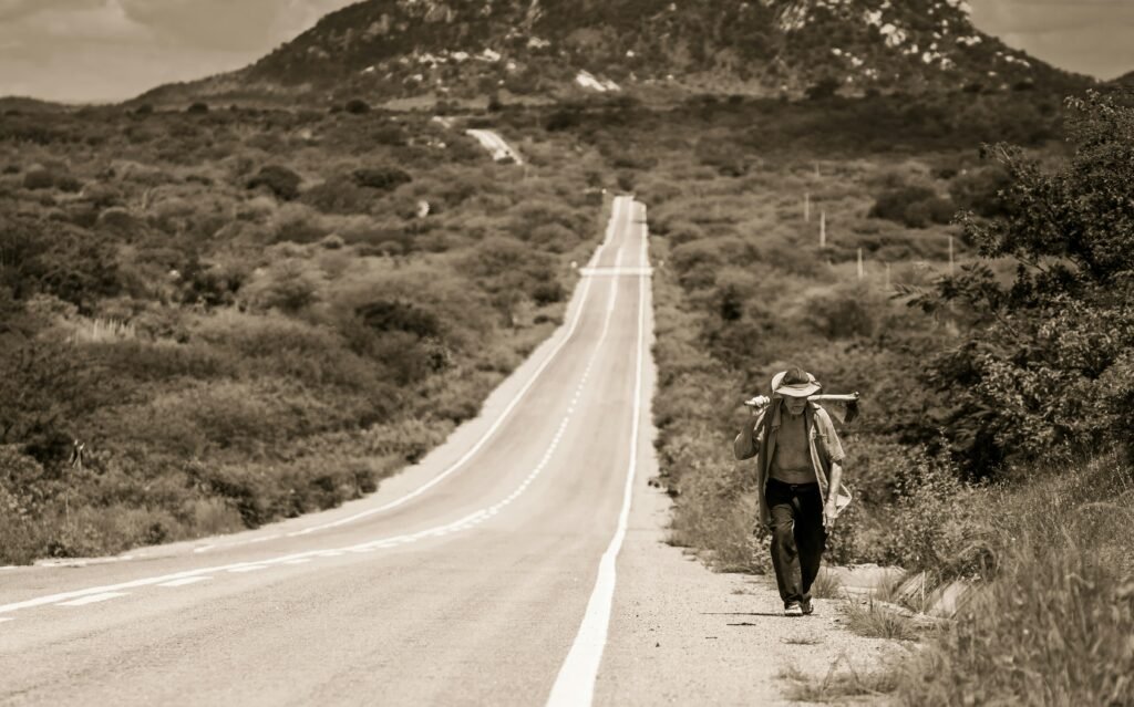 A person walking on a long road toward sunrise