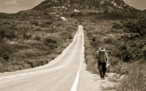 A person walking on a long road toward sunrise