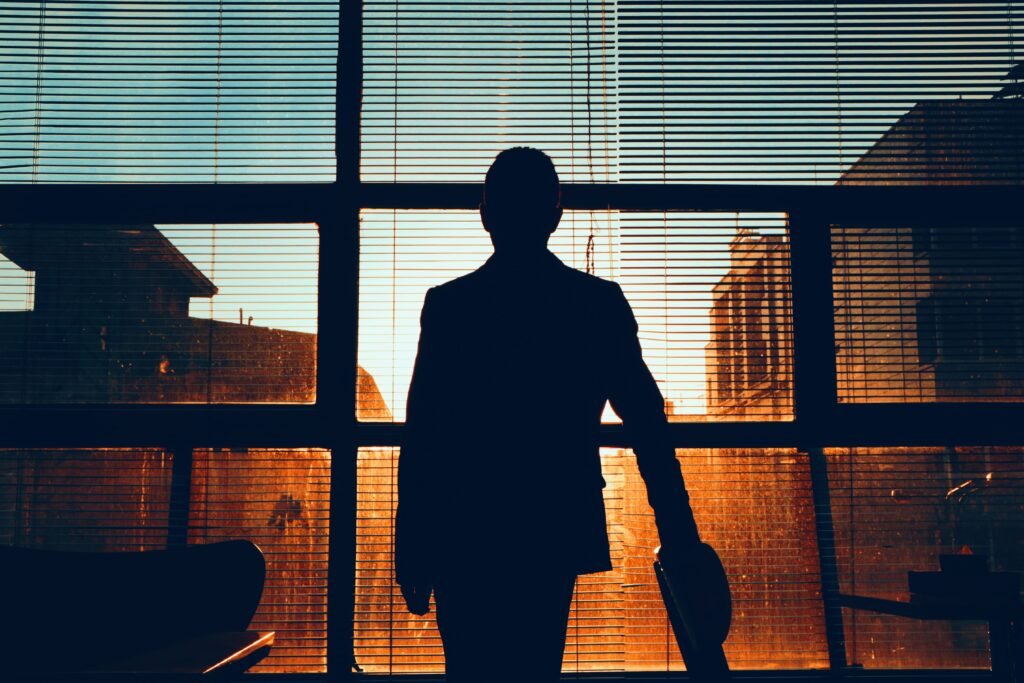 A person standing near a window or walking outdoors during sunrise