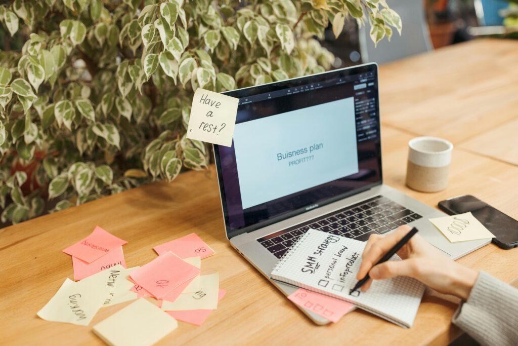 A clean desk with a notebook showing three main priorities beside a laptop and a small checklist