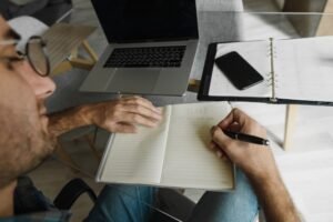 A person sitting at a desk with a notebook, phone turned face down, and a clear priority list