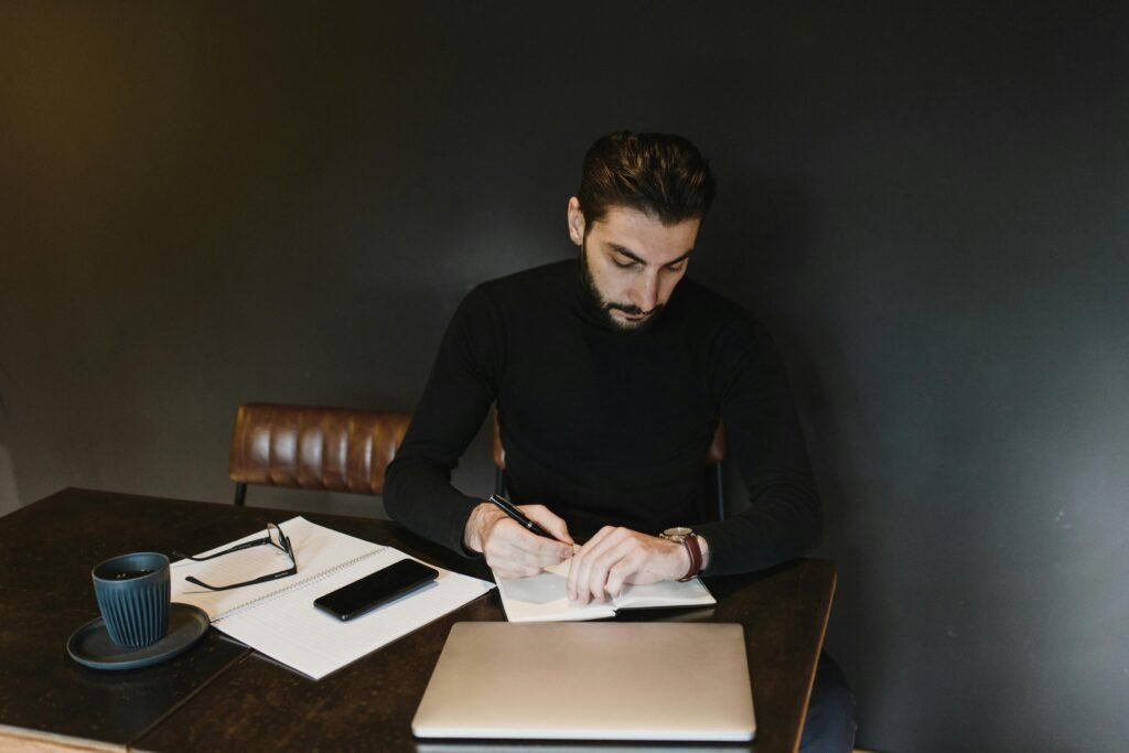 A professional sitting calmly at a desk with a laptop, notebook, and organized task list