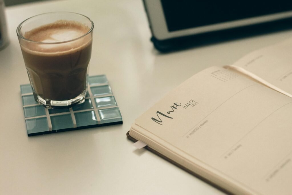 A clean desk with a weekly planner, calendar, laptop, and organized notes