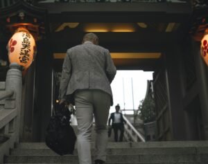 A professional walking up clear steps toward a bright office skyline