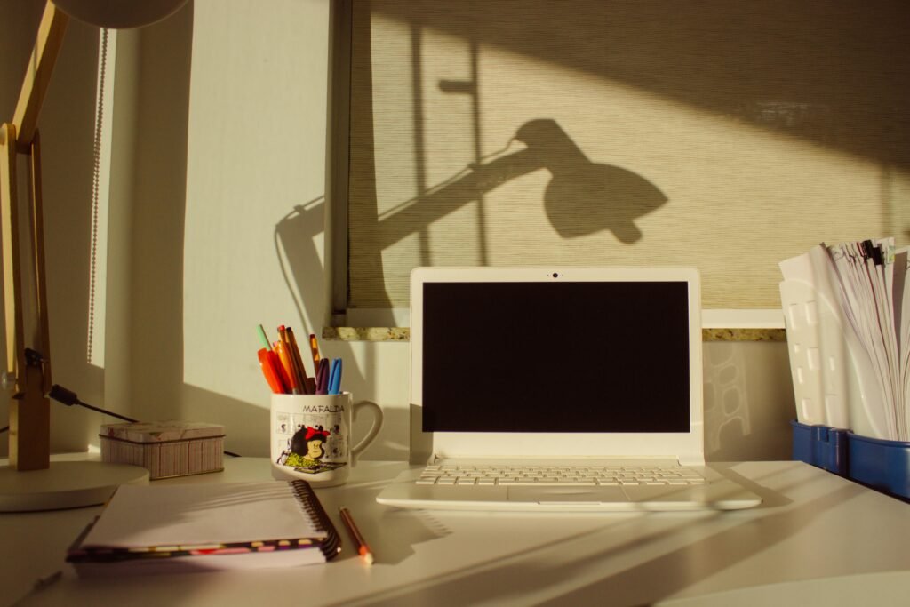 A calm workspace with a notebook, pen, and laptop on a clean desk, with soft natural light