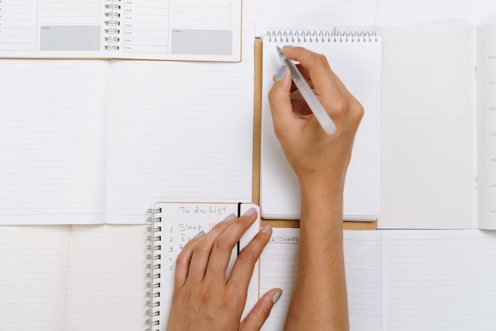 A clean desk with a notebook, calendar, pen, and simple task list
