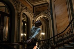 A person standing at the bottom of a staircase looking upward toward light