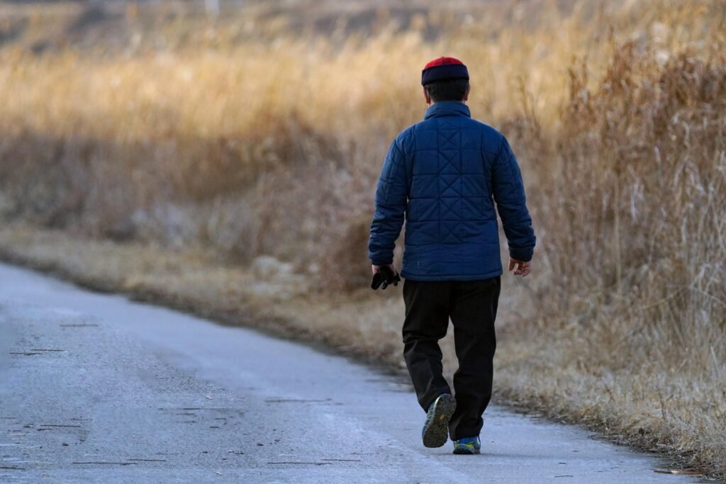 A person walking forward on a quiet road during cloudy weather