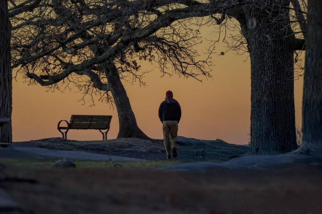 A person walking peacefully outdoors during sunrise or sitting with a journal in a calm space,