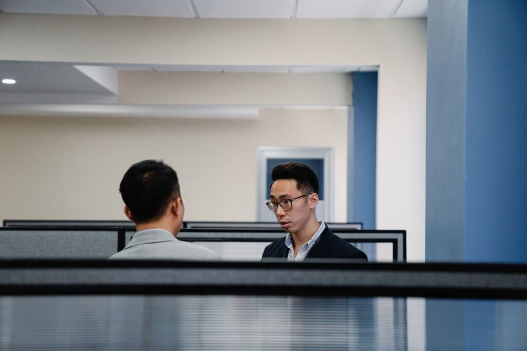 A calm professional conversation between colleagues in an office, with one person listening attentively