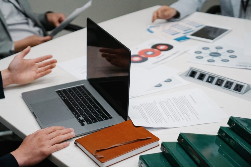 A confident professional working at a desk or presenting in a meeting, with a notebook, laptop, and skill-development plan nearby