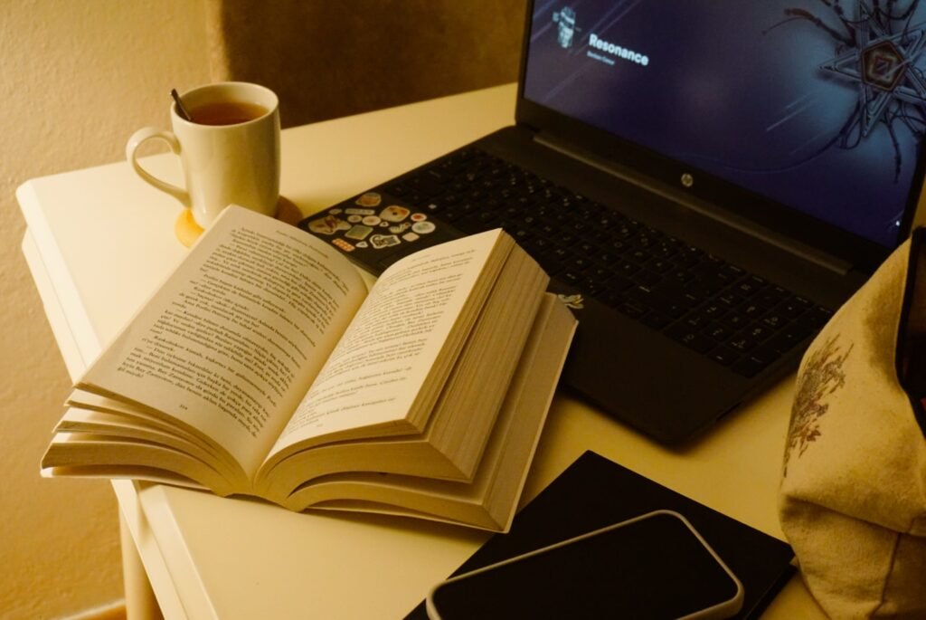 A peaceful workspace with a closed laptop, notebook, cup of tea, and soft natural light
