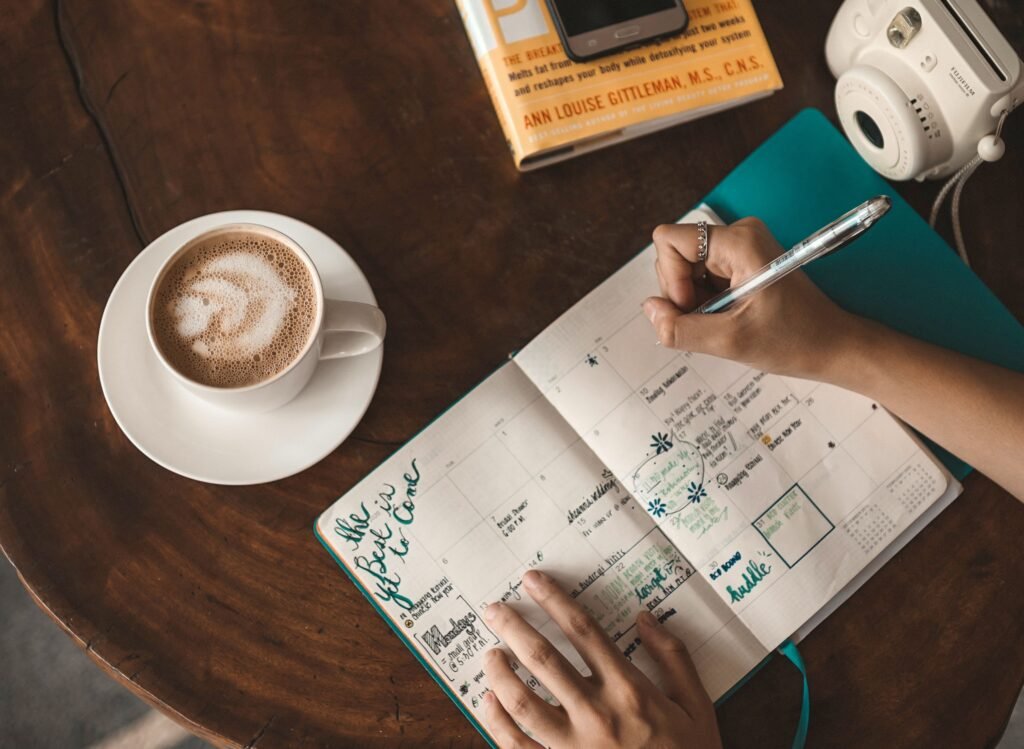 a cup of coffee, and a notebook showing daily goals