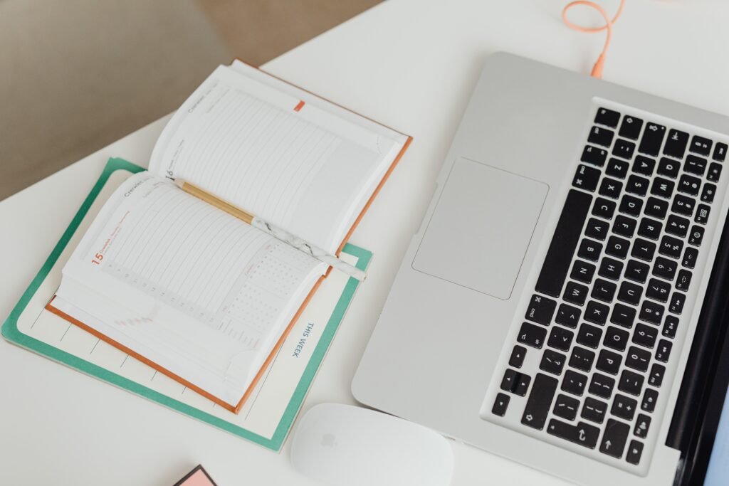 A clean desk with a notebook, calendar, laptop, folders, and a simple task list