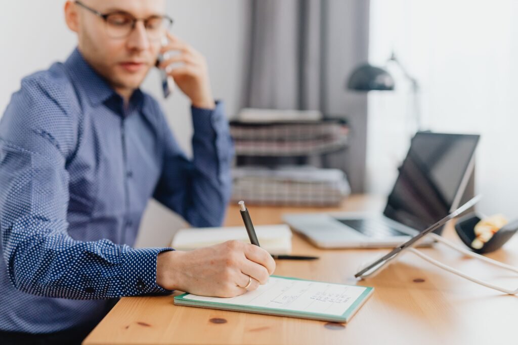 A busy professional working with a simple task list, calendar, and laptop