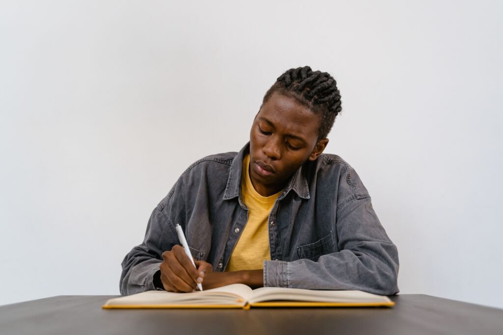 A focused person writing personal standards and goals in a journal at a clean desk
