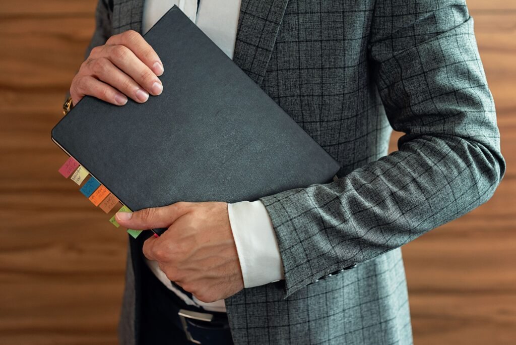 A person standing confidently on a clear path while holding a notebook or planner