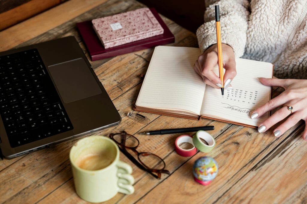 A calm person planning small life goals in a notebook at a clean desk, with a cup of coffee and soft natural light