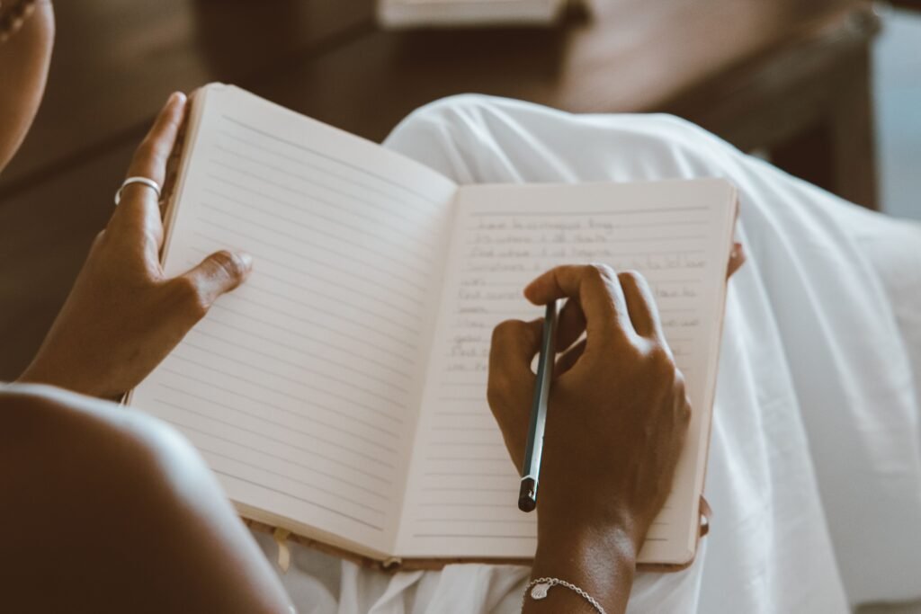 A person sitting with a notebook in a calm environment, writing thoughts and goals