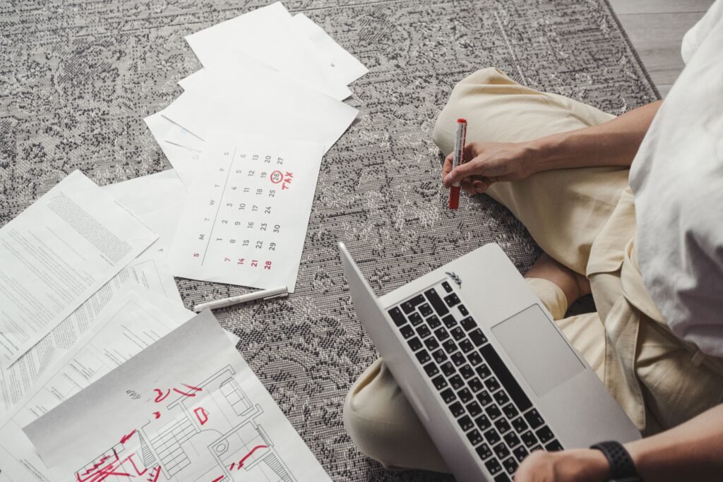A person reviewing a skill-development notebook beside a laptop, calendar, and progress checklist