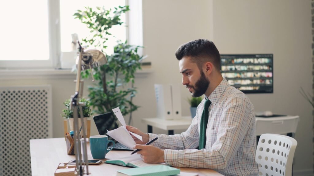 A focused professional reviewing a task list, calendar, and laptop at a clean desk
