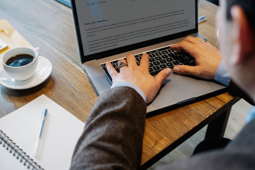A professional reviewing a resume and career plan on a laptop with a notebook, calendar, and coffee nearby