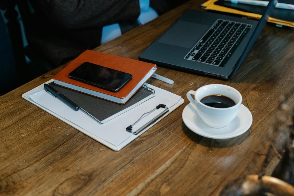 A clean weekly planner on a desk with a notebook, pen, coffee, and laptop