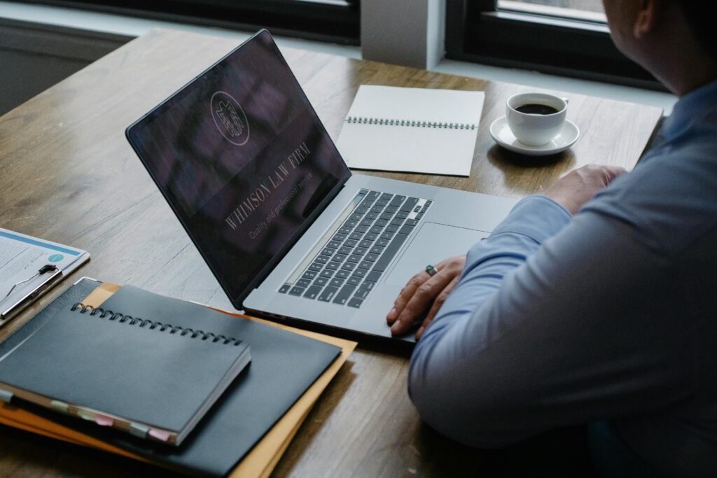 A focused job seeker working on a laptop with a resume, notebook, and coffee on a clean desk