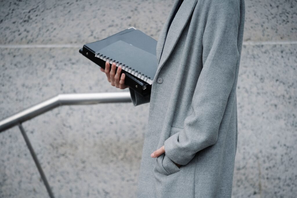 A professional standing at a career crossroads, looking at different signs or paths, with a notebook in hand