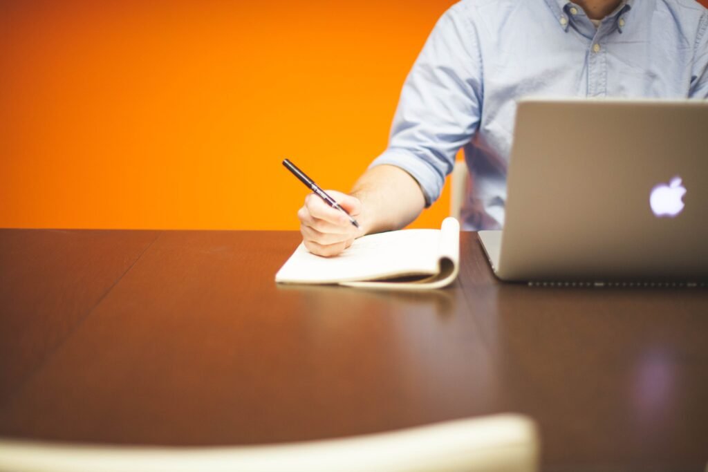 A professional writing notes in a notebook at a desk