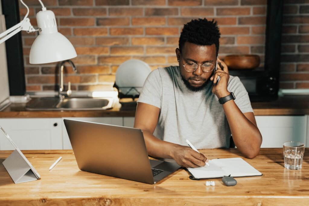 A focused person working at a clean desk with a laptop, notebook, and phone placed away
