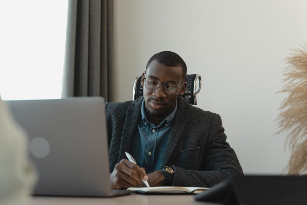A thoughtful professional sitting with a notebook and laptop, reviewing a career plan calmly