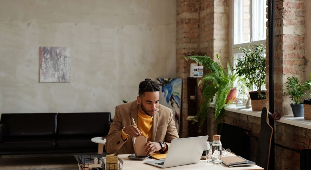 A professional sitting at a desk with a resume, laptop, and notebook, looking thoughtfully toward a window